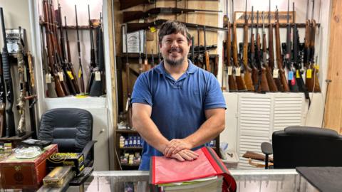 James Rabun in his family's gun store, surrounded by different kinds of guns