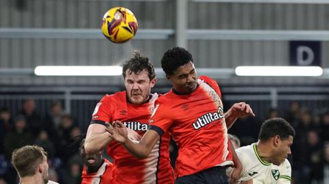Luton players challenge for the ball