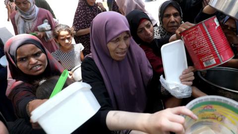 Palestinians, including children, who are struggling with hunger wait in line to receive hot meals distributed by the charity organizations while Israel's destructive attacks on the Gaza Strip continue as the humanitarian crisis in the region is increasing at Nuseirat Refugee Camp of Deir al-Balah, Gaza on June 30, 2025.