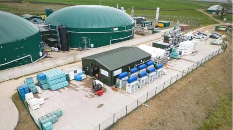 A carbon capture plant with a large green domed roof and various other buildings around it