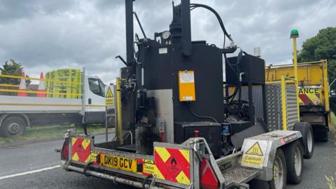 A pothole repair machine driving down a road.