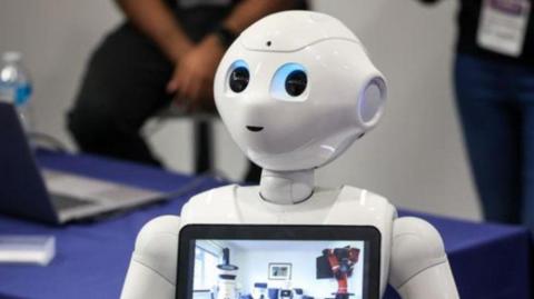 A white robot, with the image showing its head and the top part of its body. A screen is on its chest.