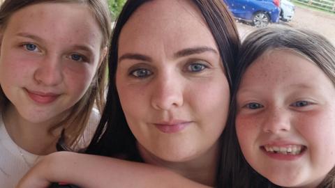 Laura and her two daughters. They are smiling at the camera.