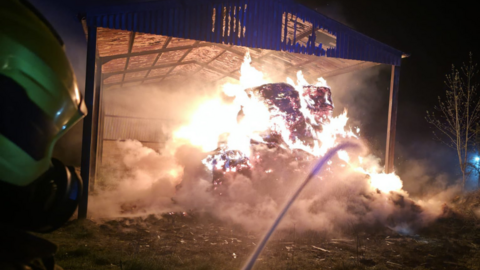 A firefighter spraying water at a major fire inside a barn