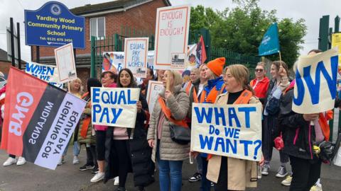 Striking workers on a picket line holding signs