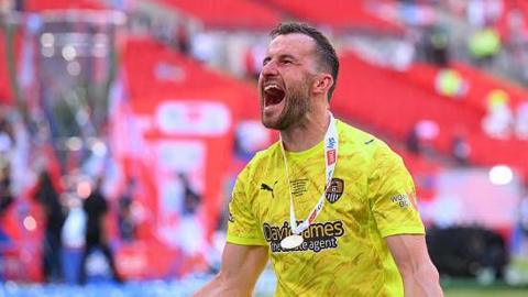 Notts County goalkeeper James Belshaw celebrating his side's promotion to League One.