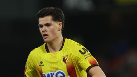 A close-up of forward Luca Kjerrumgaard playing for Watford in their yellow and red home kit