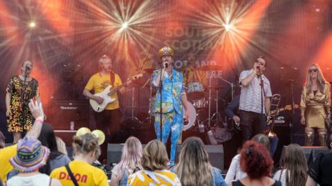 Colonel Mustard and the Dijon 5 - wearing their signature yellow accessories - perform to a small crowd