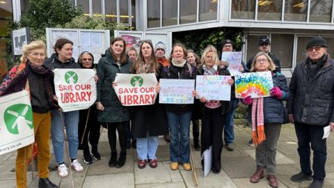 Roughly a dozen people holding placards stood together for a picture outside Hove Town Hall.