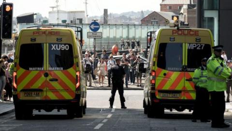 Police officers standing guard alongside police vans outside a court hearing of a violent offender.