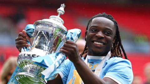 Manchester City Jeremy Doku smiles as he holds the FA Cup