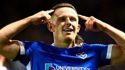 Colby Bishop points to his temples after scoring Portmouth's second goal against Ipswich