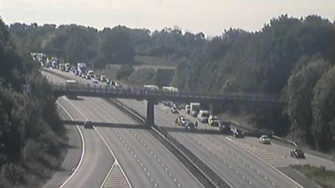 Long queue of vehicles on the M1 motorway on one side with the other empty.