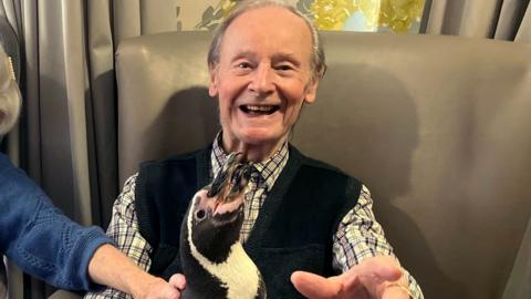 Resident Les Clarkstone, 89, holding a penguin for the first time in his life