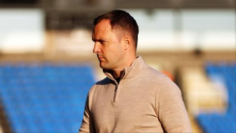 Birmingham City manager Chris Davies in a grey quarter zip top with a focused look on his face.