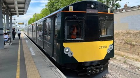 A black and yellow GWR train sitting at a platform.