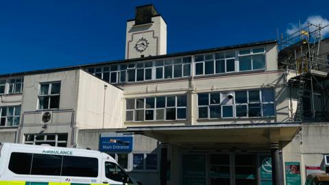 Kent and Canterbury Hospital, which is a white, multi-storey building with a clock on a tower above the main entrance.