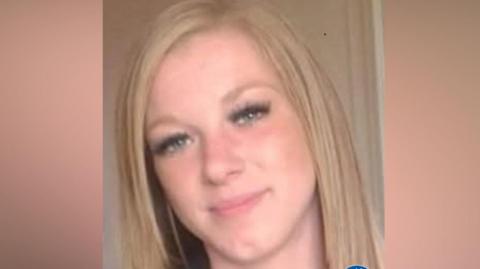 A woman with long blonde hair smiles in a selfie.