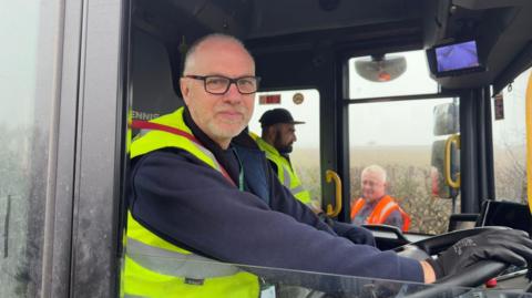 Keith Sayers behind the wheel of a bin lorry, looking at the camera