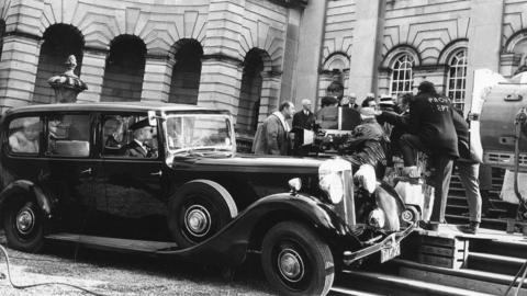 A black chauffer-driven vehicle pulls up to Castle Howard, with a film crew also in view of the photo.