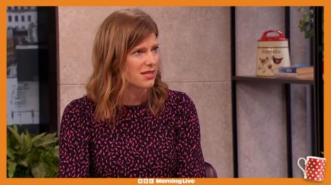 Colletta Smith in the Morning Live studio, with a pink and black long sleeve dress on.