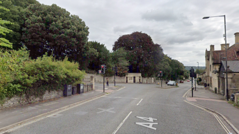 A Google Maps street view of a road junction in Bath. An image of a red traffic light and cars turning in.