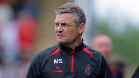 Michael Skubala looks over his right shoulder as he walks along the pitch during a pre-season game
