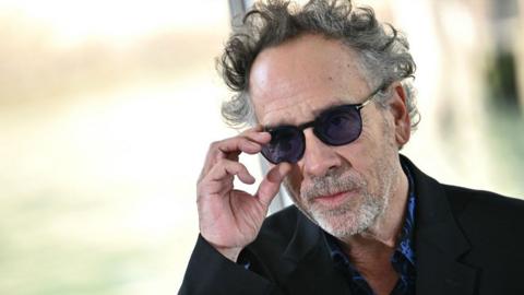 US director Tim Burton looks over his sunglasses as he arrives at the 81st Venice International Film Festival at Venice Lido in August 2024