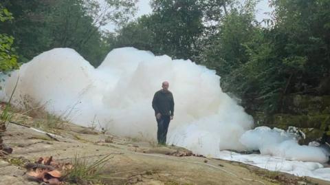 Man stood next to huge white foam pile