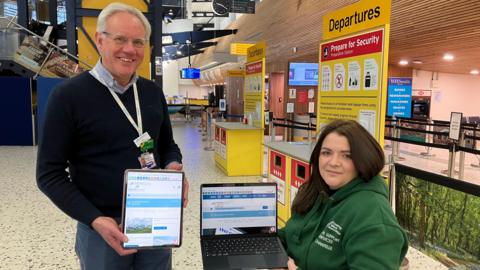 On the left is Mal Meecham, Guernsey Ports Services Manager, who is holding an IPad with the website on its screen. and Chantelle Tucker, Guernsey Blind Association’s Vision Support Services Officer, holding a laptop and displaying the new ap on Guernsey Airport’s website.