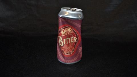 A crushed can of bitter beer made by Moor brewery. The label is a mix of red and maroon.