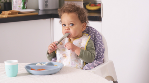 Baby with spoon in their mouth.