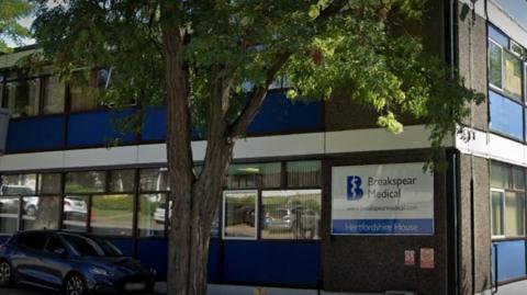 The exterior of Breakspear Medical in Hemel Hempstead. It is a large, grey concrete building with a large tree at the front. 