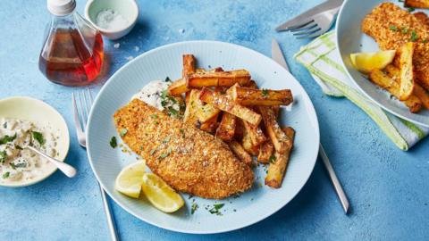 A plate of fish and chips with a side of lemon and tartare sauce.