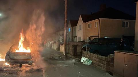 A car burns after it has been set on fire in a dark residential street