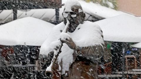 A statue of a jazz musician playing a horn is covered in snow in new orleans.