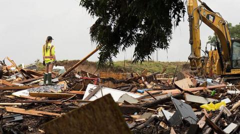 Workers operate heavy machinery to clear debris after massive flooding 