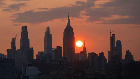 The sun is shrouded in smoke as it rises behind the Manhattan skyline earlier in July. 