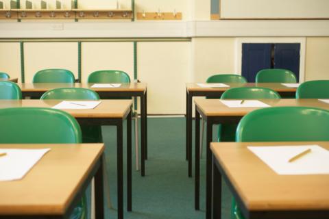 Empty classroom with pieces of paper and pencils on tabletops