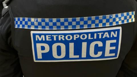 Black uniform with blue and white Sillitoe tartan and "Metropolitan Police" writing