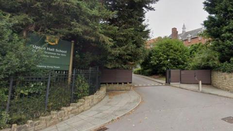 A green sign located at the entrance gates to the school includes the words Upton Hall School Catholic Grammar for Girls and 'inspiring young people' 