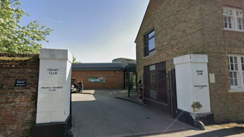 The entrarnce of the Odney Club, which is bordered by two large white plinths aside a country house in Cookham. 