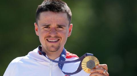 Tom Pidcock holding his Olympic gold medal