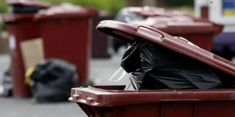 Black bins poking out of red bin, with more red bins in the background.