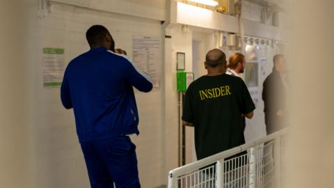 Prisoners walk through a hall in HMP Pentonville