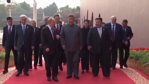 Vladimir Putin, Xi Jinping and Kim Jong Un waking, leading a group of people who follow behind them