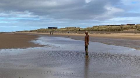 A view of Crosby beach showing an iron man and promenade