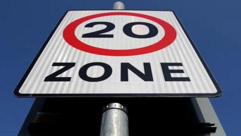A 20mph road sign against a clear blue sky
