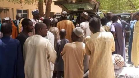 Traders and buyers stand as good are loaded into a car at the Jilli market along the Yobe-Borno state border in Nigeria