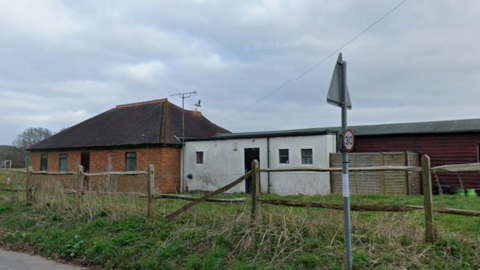 Derelict building in a field with a street sign in the foreground